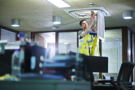 Technician performing preventative HVAC maintenance in an office building